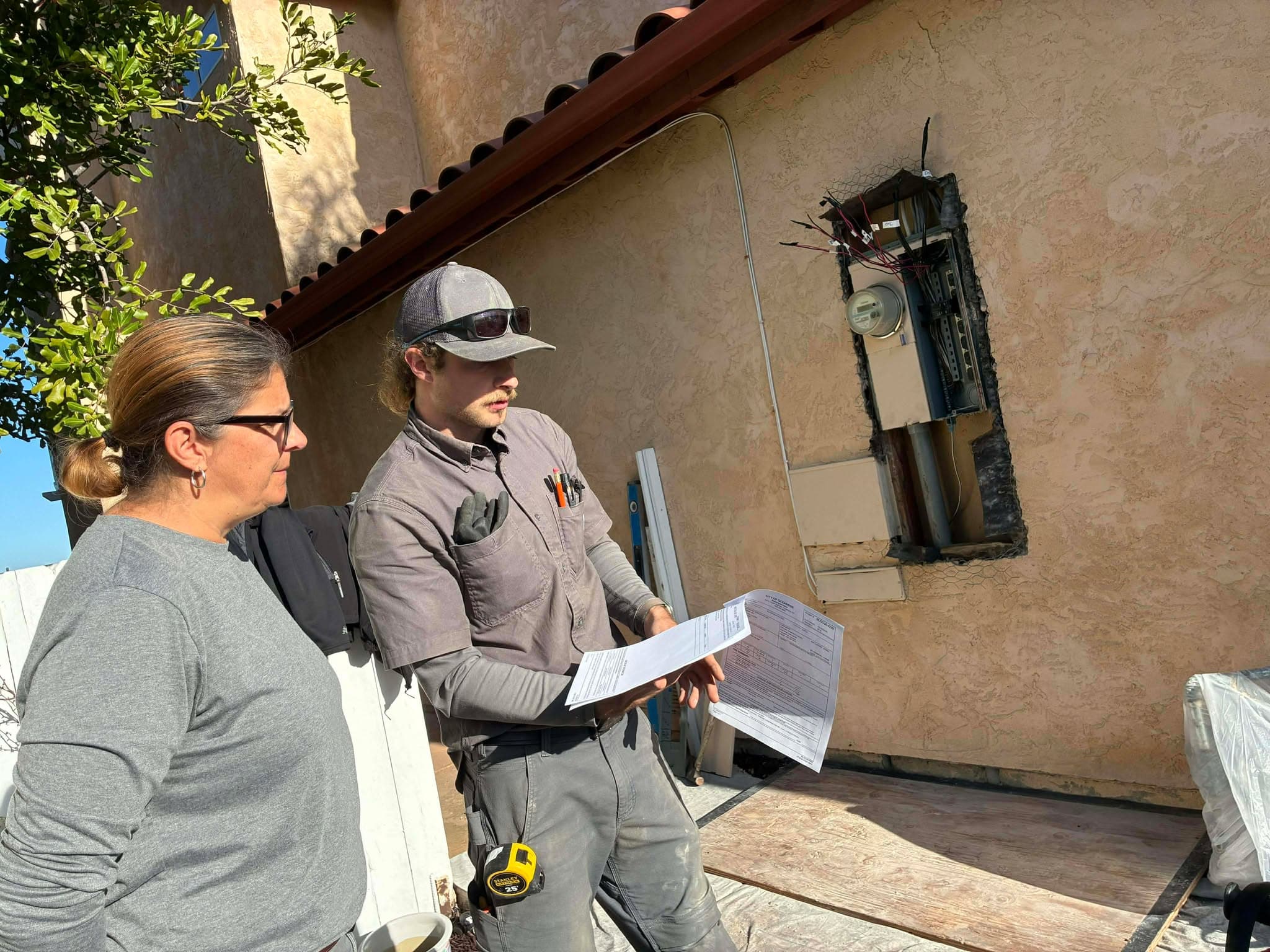 MIZO Electric reviewing permit paperwork with a homeowner beside an electrical panel upgrade